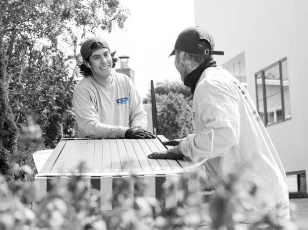Two soalr installers smiling and talking while unpacking a box of 440w solar panels
